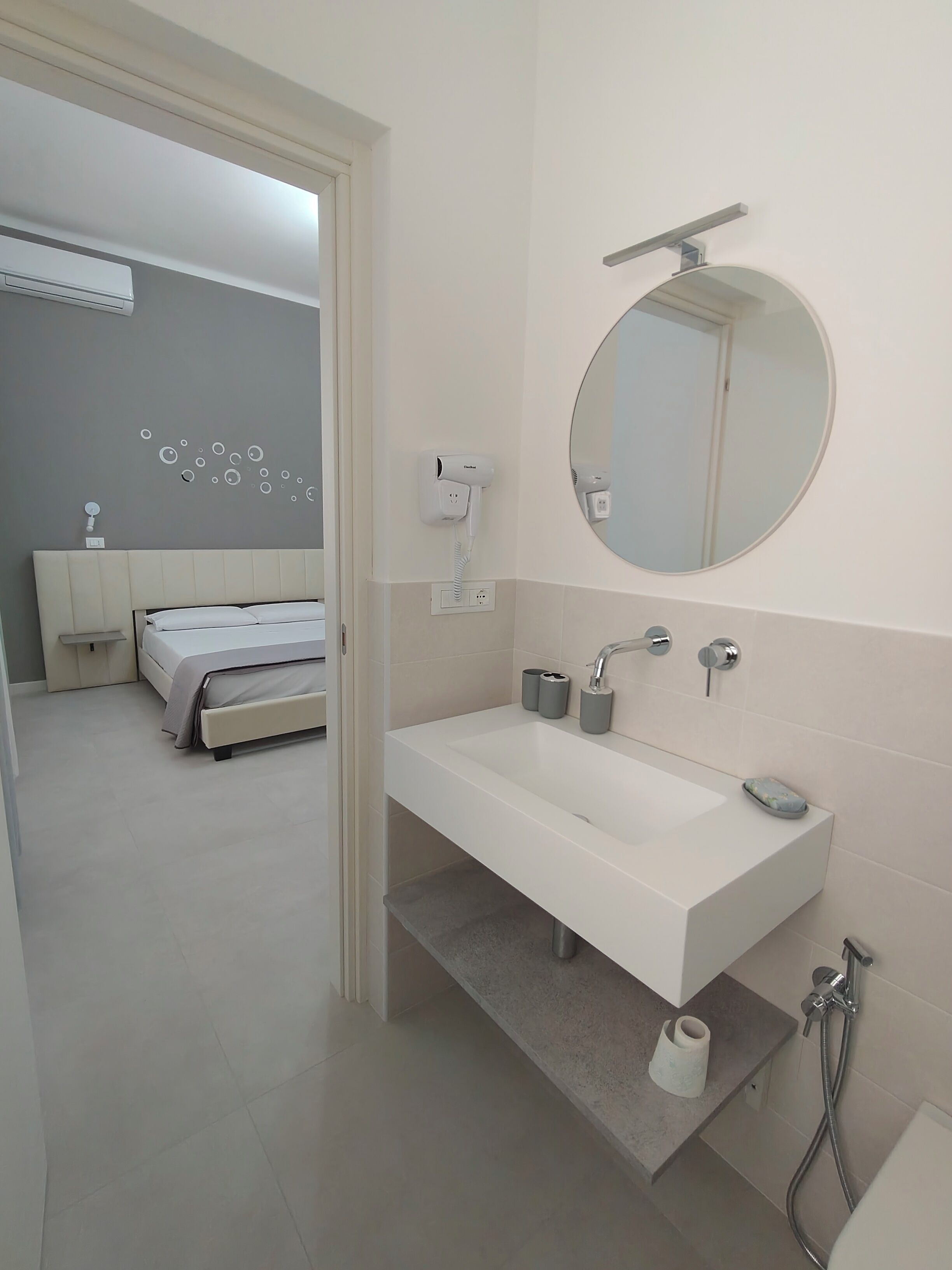 Ein modernes Badezimmer mit einem weißen Waschbecken, Spiegel und Dusche.