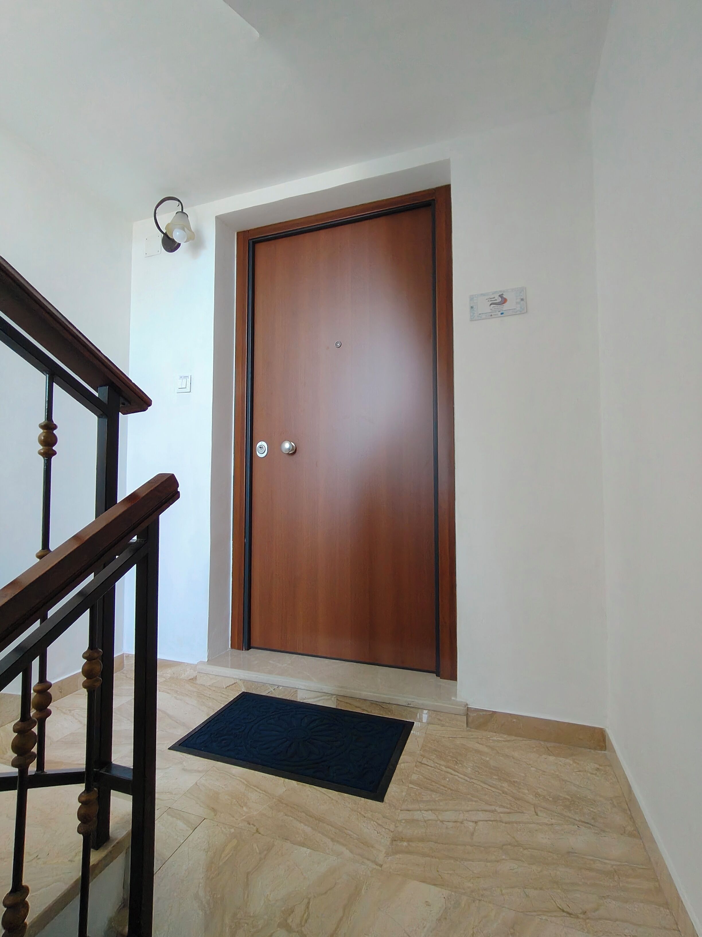A wooden door with a doorknob and a light switch above it.