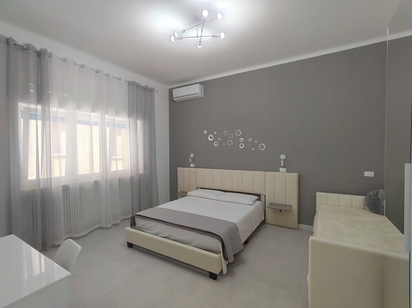 Et moderne soveværelse med seng, to sengeborde, et skrivebord og en stol.