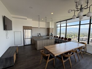 Une cuisine moderne dotée d’un grand îlot central, d’un coin repas avec des chaises en bois et d’une grande fenêtre offrant une vue sur la ville.