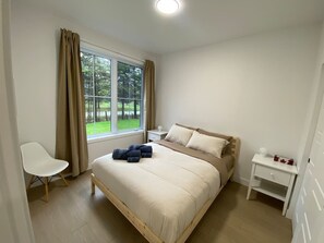 A bedroom with a bed, a chair, a nightstand, and a window with curtains. - Le Relais Austin 4 — Spa, Nature & Adventure (Austin)