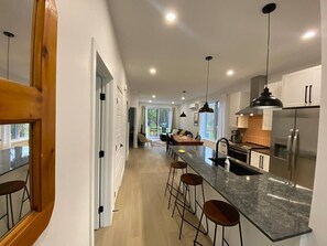 A modern kitchen with a central island, bar stools, stainless steel appliances, and pendant lighting. - Le Relais Austin 4 — Spa, Nature & Adventure (Austin)