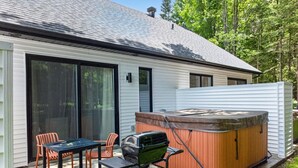 Een huis met een terras, een jacuzzi en een barbecue.