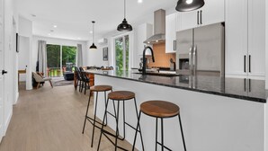 A modern kitchen with a central island, bar stools, and pendant lighting. - Le Relais Austin - Full Property (4 Units-6 beds) (Austin)
