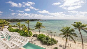 Ein Strandresort mit Pool, Palmen und freiem Blick auf den Ozean.