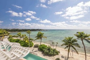 Ein Strandresort mit Pool, Palmen und freiem Blick auf den Ozean.