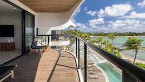 Ein Balkon mit geschwungener Reling, der auf einen Strand und das Meer blickt.