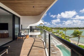 Ein Balkon mit geschwungener Reling, der auf einen Strand und das Meer blickt.