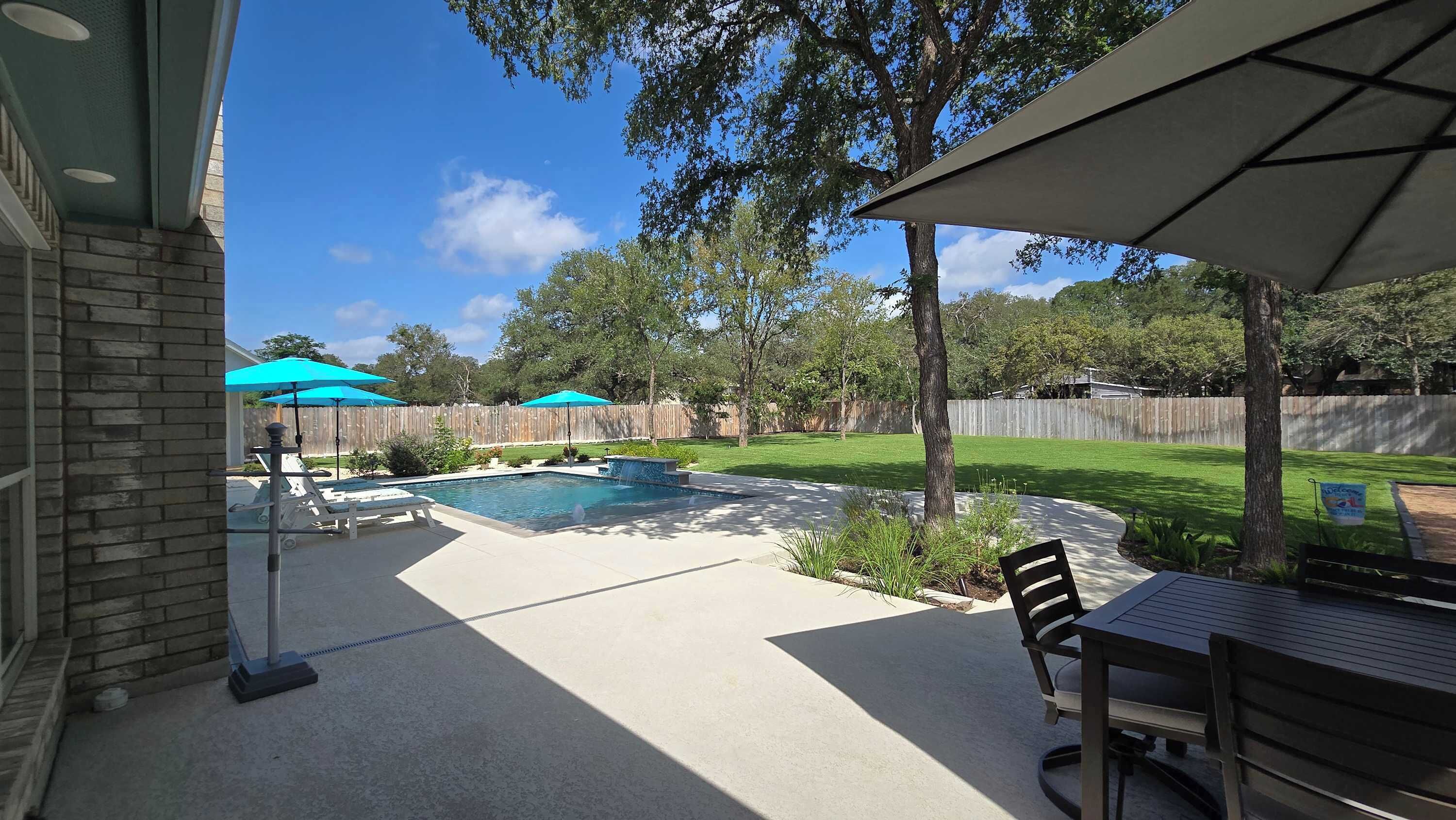 Ein Garten mit Swimmingpool, Terrassenmöbeln und Holzzaun.