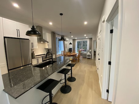 A modern kitchen with a central island, bar stools, and pendant lighting.. Le Relais Austin 1 — Spa, Nature & Adventure