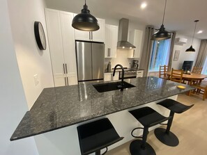 Una cocina moderna con una isla central, electrodomésticos de acero inoxidable e iluminación colgante.