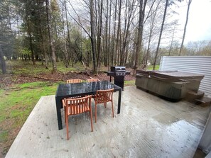 An outdoor patio with a table and chairs, a grill, and a hot tub. - Le Relais Austin 1 — Spa, Nature & Adventure (Austin)