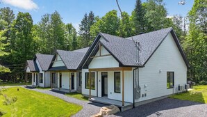 A row of modern, single-story cabins with a gravel driveway and a grassy lawn.