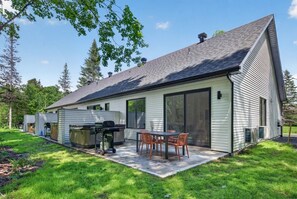 A modern house with a patio, outdoor grill, and a large sliding glass door.