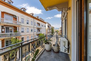 A balcony with a metal railing, potted plants, and a view of adjacent buildings. - Charming 1BR Apartment in Shkodër City Center by PikHost (Shkodër)