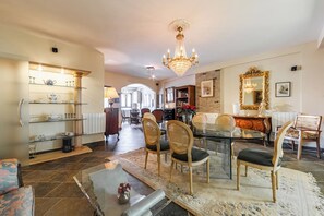 Un salon spacieux comprenant un coin repas, un lustre et une cheminée.