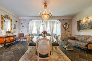 A dining area with a round table, chairs, a chandelier, and a sofa. - Charming 1BR Apartment in Shkodër City Center by PikHost (Shkodër)