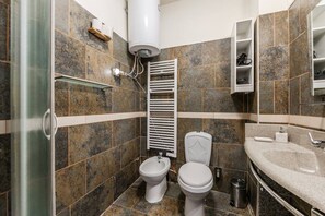 Ein Badezimmer mit Dusche, zwei Toiletten, Waschbecken und Handtuchhalter.