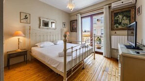 Ein Schlafzimmer mit Bett, Nachttischlampe, Kommode und einem Balkon mit Blick.