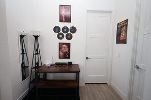 Ein Flur mit einem Holztisch, einem Spiegel und Wanddekorationen, darunter Schallplatten und ein Plakat.