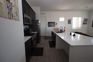 Una cocina moderna con armarios oscuros, un refrigerador de acero inoxidable, un microondas y una isla grande con pileta.