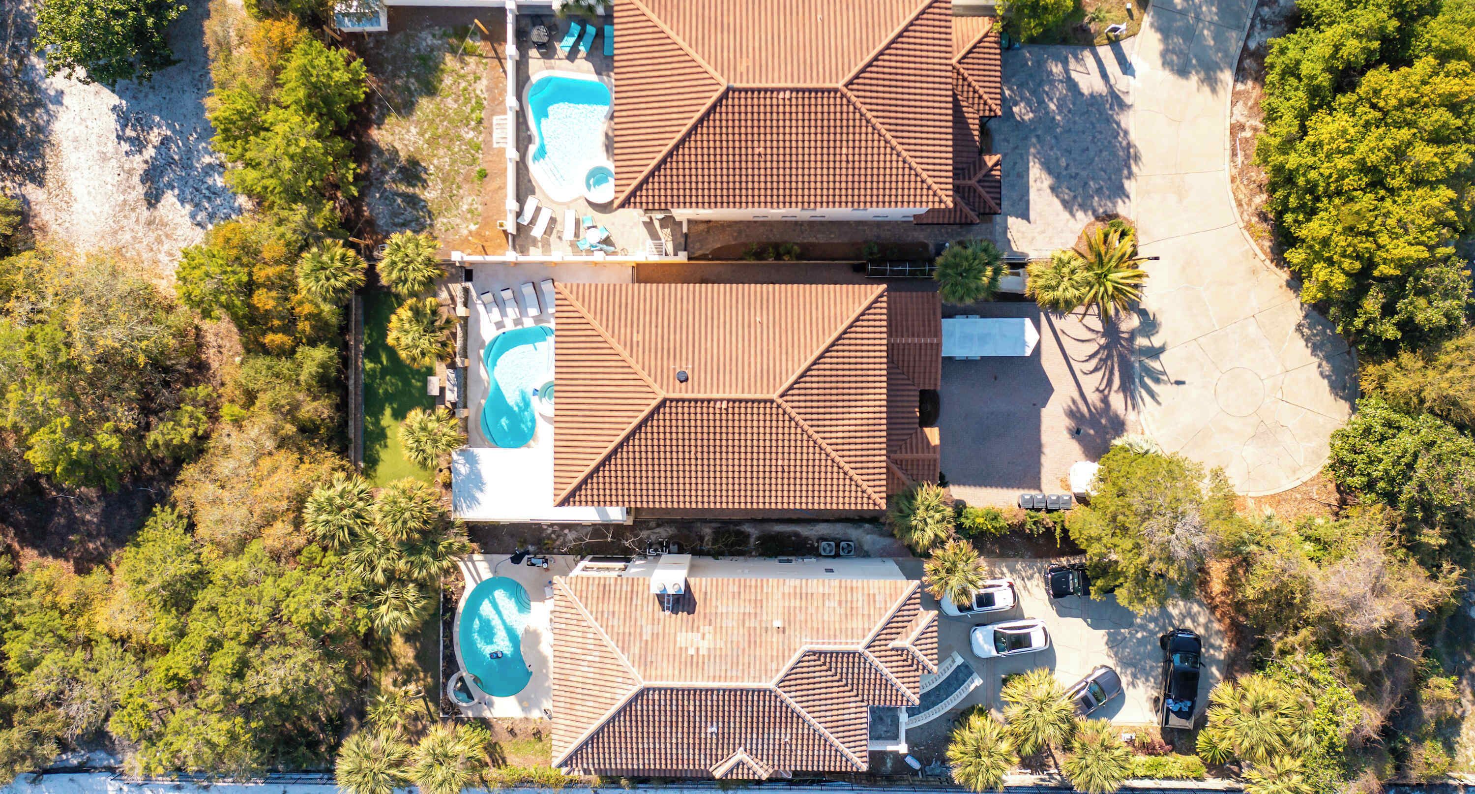 Vista aérea de una propiedad con piscina, varias habitaciones con techos de tejas y follaje circundante.
