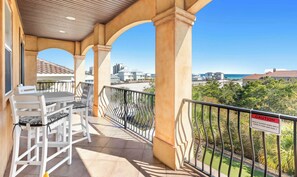 Ein Balkon mit Tisch und Stühlen, einem Metallgeländer und Blick auf das Meer und die Gebäude.