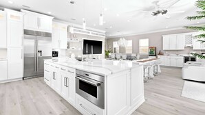 A modern kitchen with white cabinetry, stainless steel appliances, and a central island. - Miramar Beach Home, Pool, Hot Tub & Chef's Kitchen (Miramar Beach)