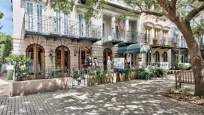 Un edificio histórico con puertas arqueadas, un balcón y una bandera.