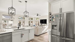 A modern kitchen with white cabinetry, a stainless steel refrigerator, and pendant lighting. - Santa Rosa Home with Private Pool, Near Beach (Santa Rosa Beach)