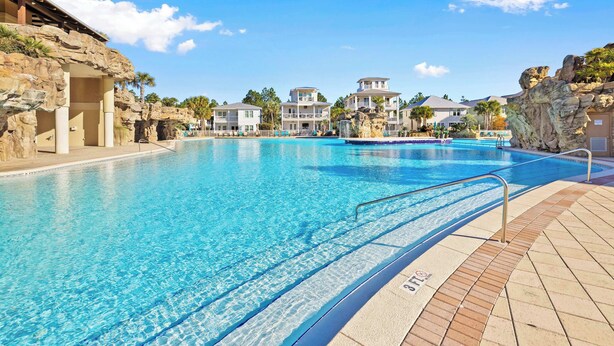 A swimming pool with clear blue water, surrounded by rock formations and a few buildings in the background. - Santa Rosa Home with Private Pool, Near Beach (Santa Rosa Beach)