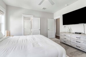 Ein Schlafzimmer mit einem großen Bett, einem an der Wand montierten Fernseher und einer Kommode mit Schubladen.