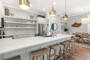 Eine moderne Küche mit weißen Schränken, Edelstahlgeräten und Holzbarhocker.