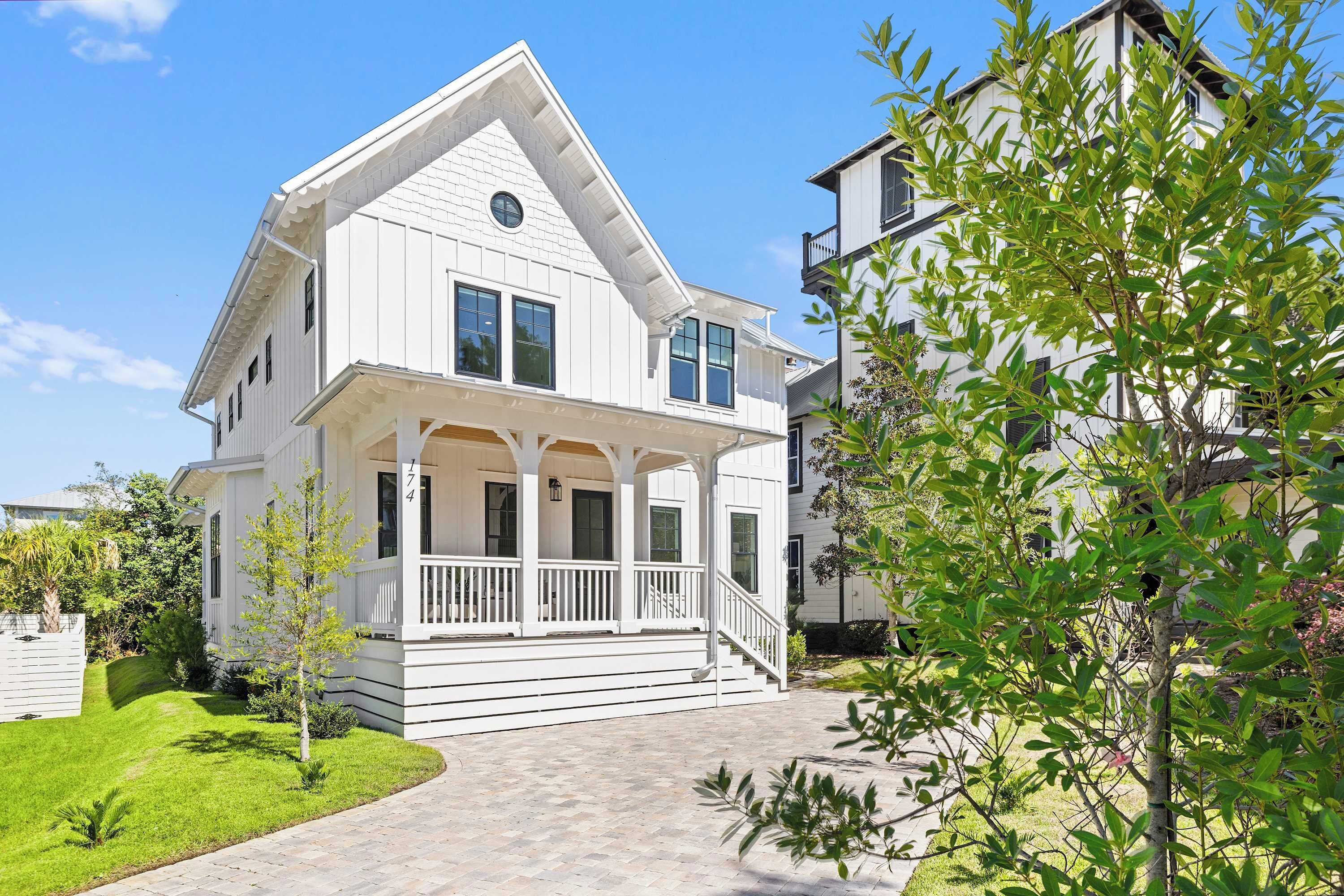A two-story house with a porch, a small tree, and a well-maintained lawn.