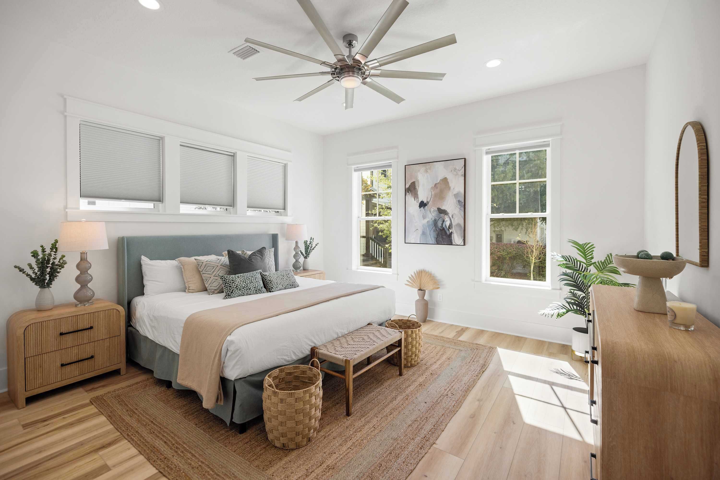 A bedroom with a bed, bedside tables, a ceiling fan, a window, and a painting.