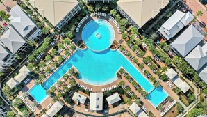 Ett flygbildsbild av ett semesterområde med en central pool, flera avslappningsområden och palmer runt omkring.