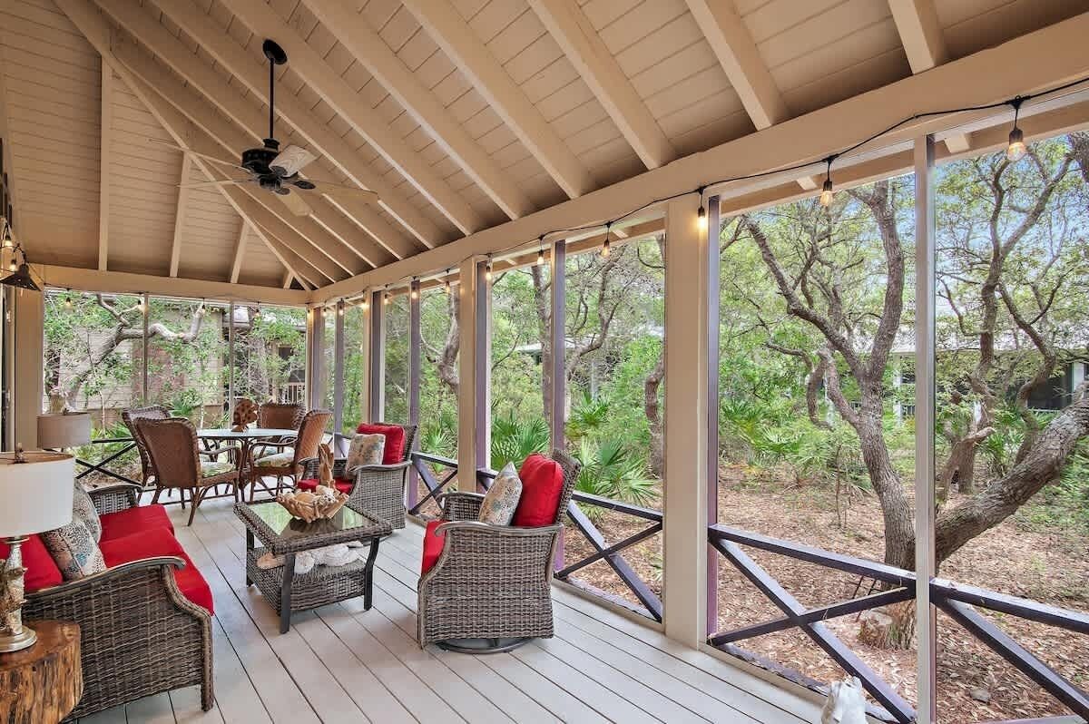 Un espacio de estar al aire libre con techo, con mobiliario de mimbre y una mesa, con vistas a un paisaje natural.