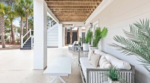 A covered outdoor seating area with a white bench, a table, and a sofa. - Santa Rosa Home with Pool, Deck & Beach Access (Santa Rosa Beach)