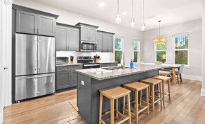 Eine moderne Küche mit grauen Schränken, Edelstahlgeräten, einer Granit-Arbeitsplatte und Holzbarhocker.
