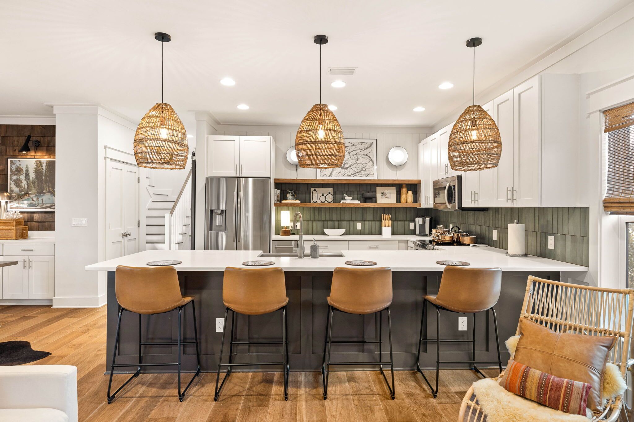 A modern kitchen with a large island, pendant lights, and bar stools.