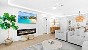 Ein modernes Wohnzimmer mit Kamin, Wand-Fernseher und Essbereich mit Stühlen und Tisch.