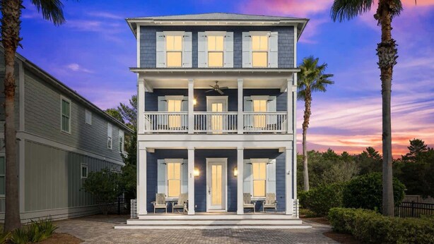 Une maison à deux étages située en bord de mer, dotée d’un balcon, d’un porche couvert et d’une allée.