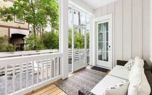 Ein Balkon mit Grill, einem weißen Sofa und einem gemusterten Teppich.