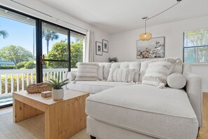 Ein modernes Wohnzimmer mit einer großen Eckcouch, einem Holztisch und Blick ins Freie.