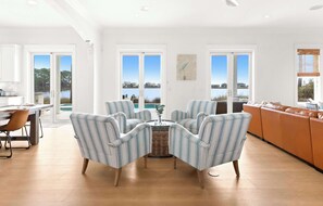 A spacious living room with a view of a lake, a dining area with a table and chairs, and a kitchen area. - Oyster Lake Estate with Pool, Dock & Golf Cart (Santa Rosa Beach)
