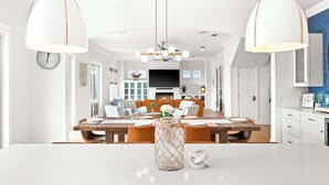 A spacious dining area with a wooden table, white chairs, and pendant lighting. - Oyster Lake Estate with Pool, Dock & Golf Cart (Santa Rosa Beach)
