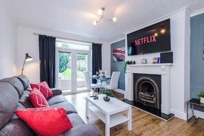 Ein modernes Wohnzimmer mit Kamin, Flachbildfernseher und Essbereich.