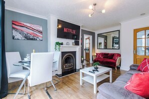 Ein modernes Wohnzimmer mit Kamin, Flachbildfernseher, Essbereich und einer gemütlichen Sitzecke.