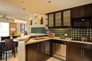 A modern kitchen with dark wood cabinets, a stainless steel dishwasher, and a green tiled backsplash. - Westin Lagunamar 2 Bedroom Villa with Balcony (Cancun)
