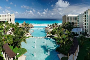 A resort with a central pool, palm trees, and a view of the ocean. - Westin Lagunamar 2 Bedroom Villa with Balcony (Cancun)